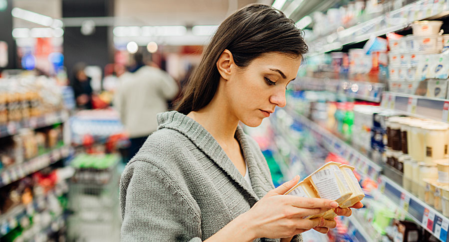 Young man in safety goggles, standing in the middle of a field examining a leaf
