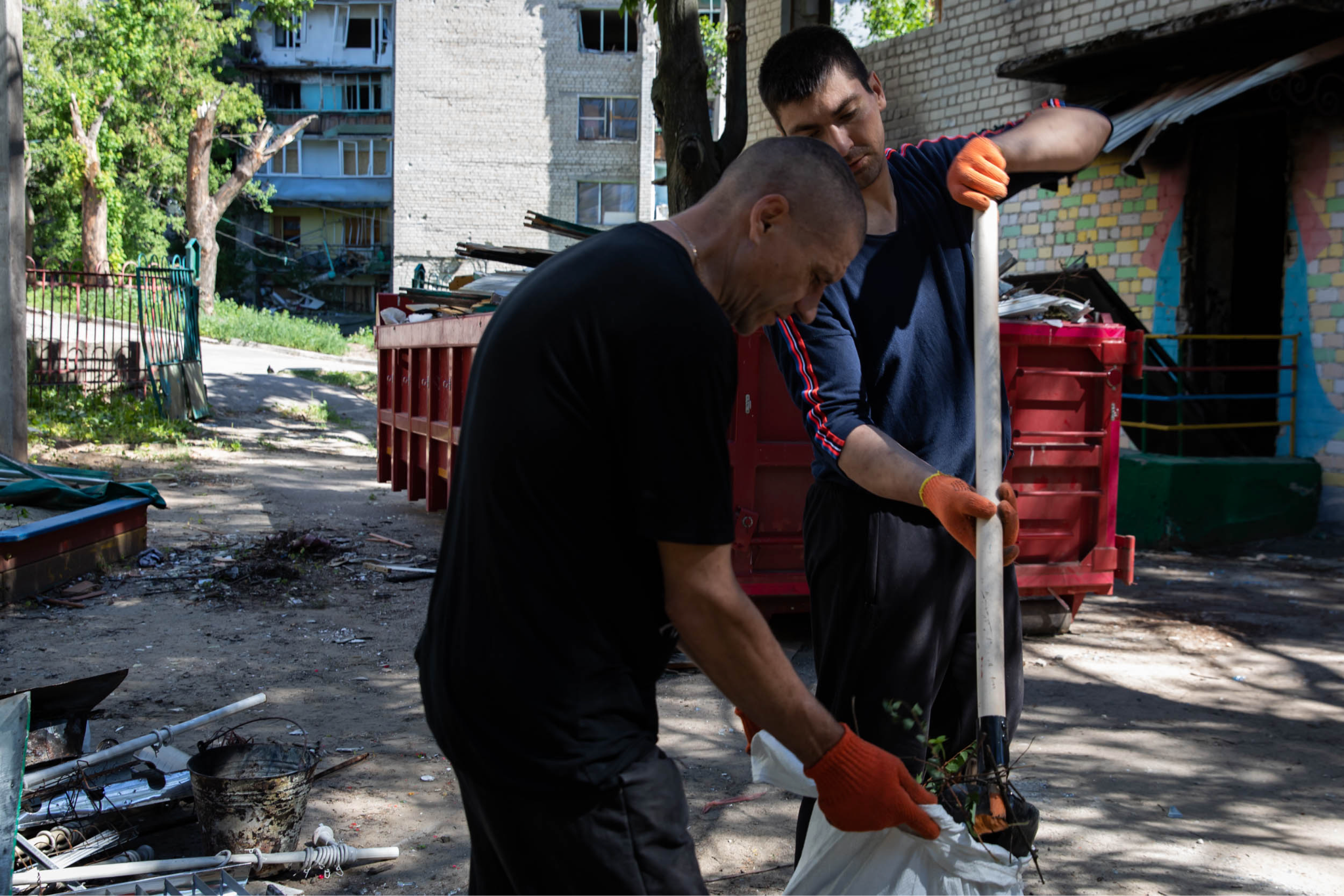 Two Chernihiv residents clearing out debris in a residential complex
