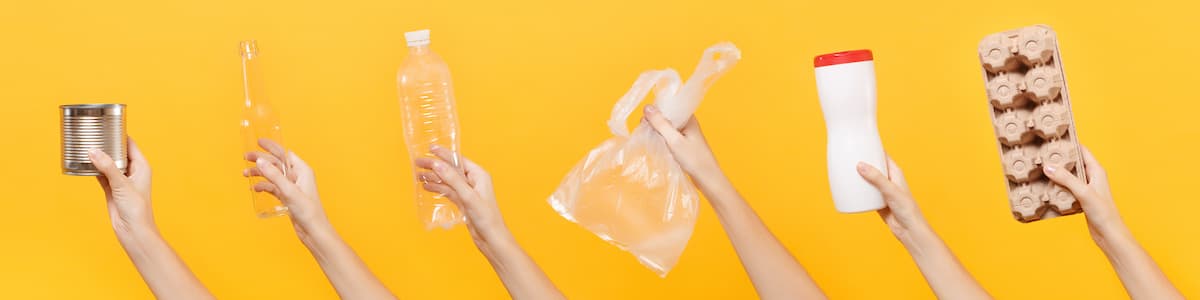 Yellow background with six arms holding up different recyclable materials