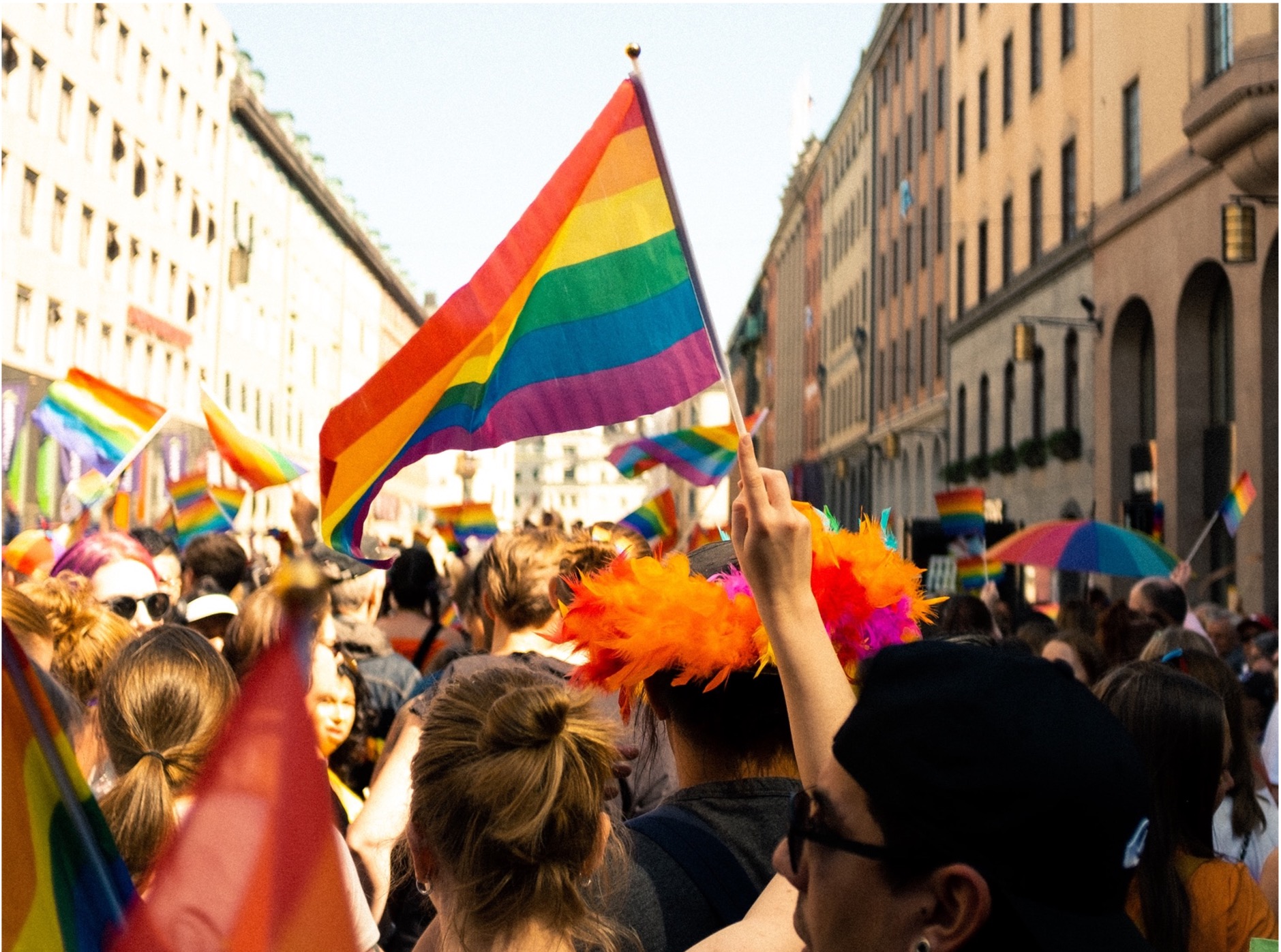 Image of people waving a rainbow flag at a Pride parade.