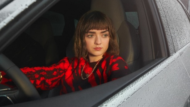 Maisie Williams sitzt bei heruntergelassenem Fenster in einem nur in Konturen zu erkennenden nassen Auto und schaut nach rechts hinaus, Szene aus dem Werbespot "Let it go" für den Audi e-tron