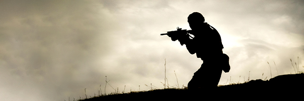 Photo of a silhouetted soldier with gun raised