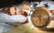 Woman in bed looking at alarm clock