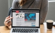 Laptop screen showing a mock news site with a woman pointing to it.