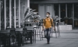 Man wearing mask walks by empty chairs outside restaurant
