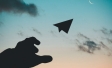 Hand throwing paper plane in air