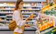 Woman wearing mask in grocery store and selecting produce. She is holding a lemon