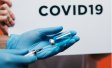 covid vaccine held by blue glove