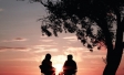 Retired couple sitting in camping chairs at sunset