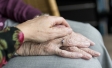 One old person's hand holding another old person' hand with ring on the ring finger