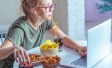 Kind mit Snacks am Laptop sitzend