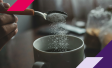 Picture of a hand pouring sweetener into a cup of coffee