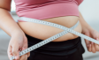 An overweight woman measuring her stomach with a tape