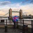 A tourist with a British (Union Jack) flag umbrella watching the sunset over Tower Bridge, London