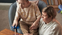 young boy with disability sat playing with his carer