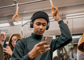Person steht in der U-Bahn und schaut aufs Smartphone