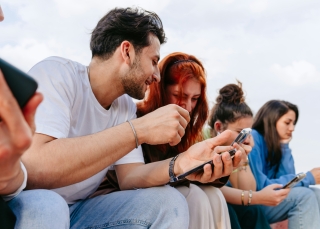 Eine Gruppe junger Menschen schaut auf ihr Smartphone