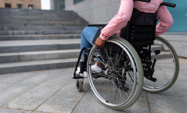 Mensch im Rollstuhl vor einer Treppe