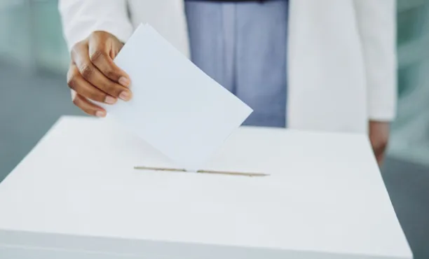 A hand casting a ballot into a box