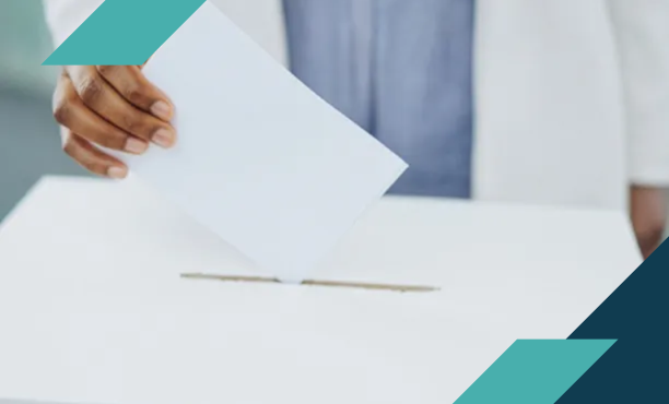 A hand casting a ballot into a box