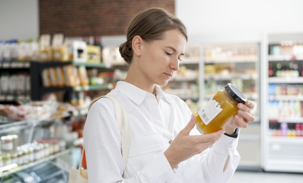 Woman reading ingredients on a bottle in the supermarket