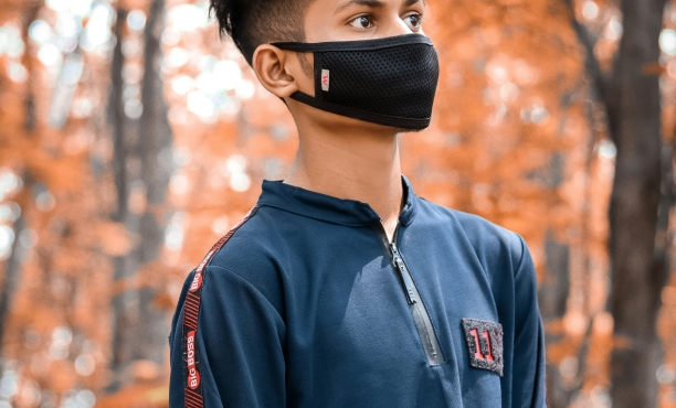 A boy in a forest with a face mask on
