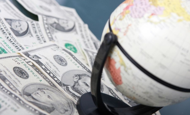 Globe resting on scattered U.S. dollar bills.