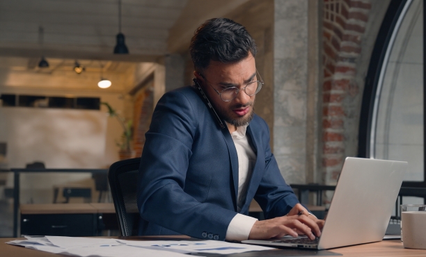 Man talking on the phone and working on the laptop looking tense