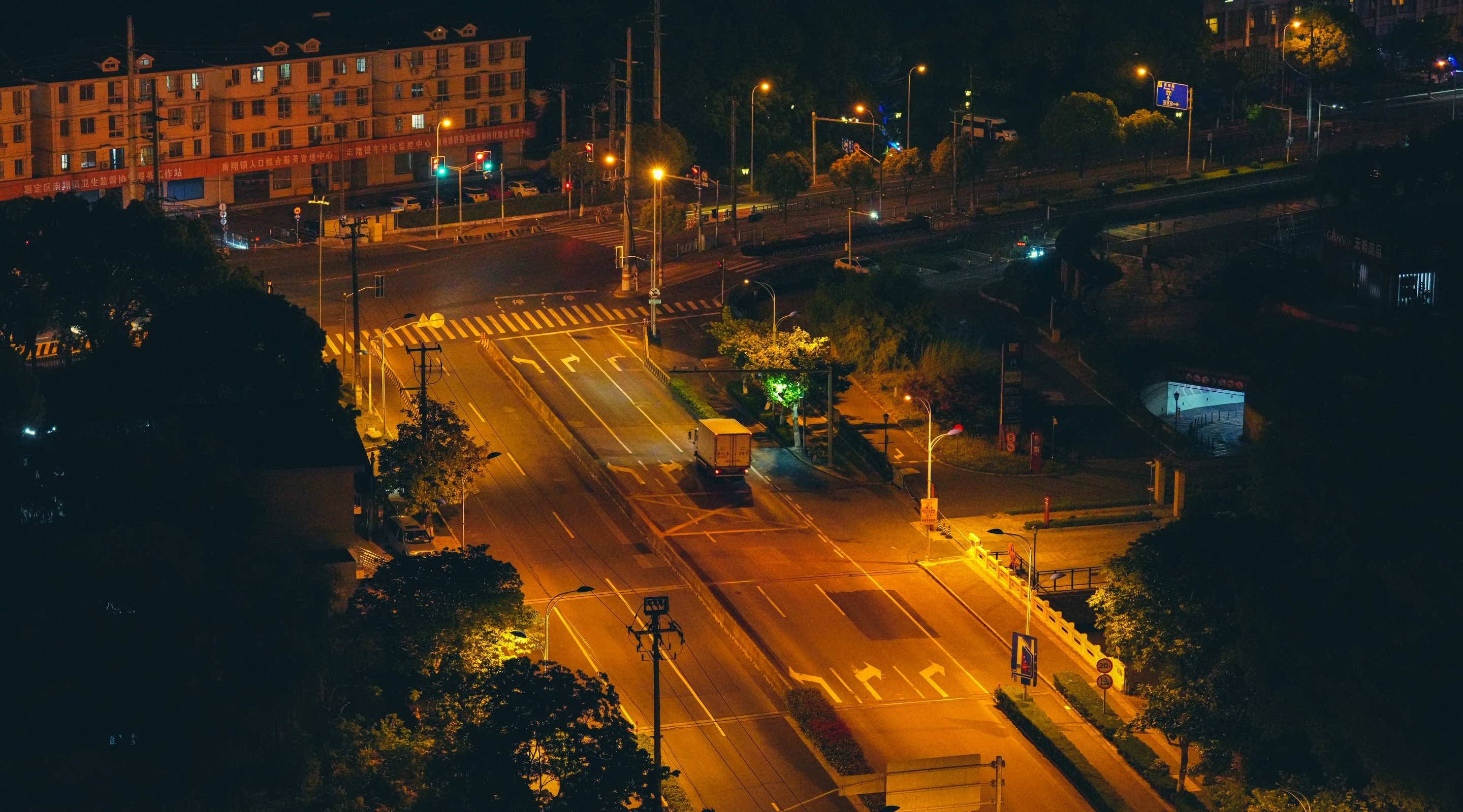 A nighttime aerial view of a brightly lit city intersection with surrounding skyscrapers