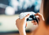 Eine Person die einen weißen Gaming-Controller bedient.