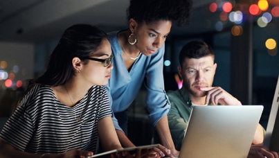 Three diverse executives working on computers in the office into the evening