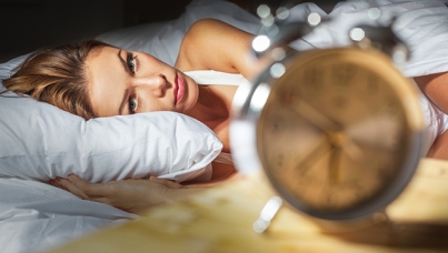 Woman in bed looking at alarm clock