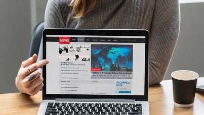 Laptop screen showing a mock news site with a woman pointing to it.