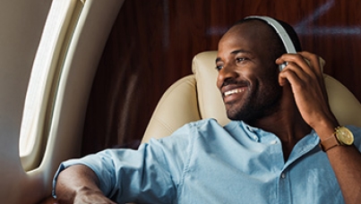 how do the European Affluent travel the world? | man wearing headphones on plane | Ipsos | Europe Affluent Survey