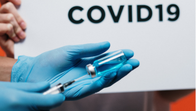 covid vaccine held by blue glove