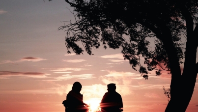 Retired couple sitting in camping chairs at sunset