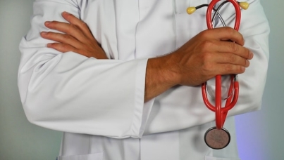 a doctor in white coat with crossed arms holding a stethoscope