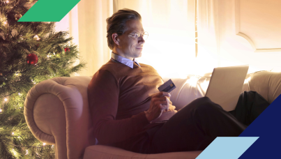 Man shopping on a laptop next to a Christmas tree