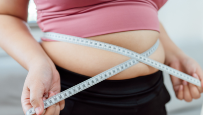 An overweight woman measuring her stomach with a tape
