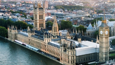 Aerial view of the the Elizabeth Tower which contains the bell Big Ben and the Houses of Parliament for the UK along the Thames River at dusk