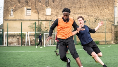 young men playing football in a playground