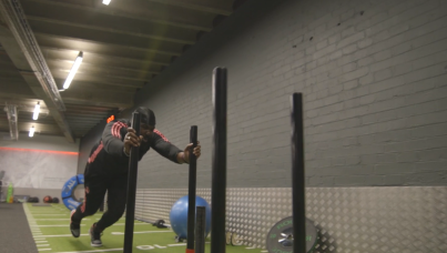 Man in gym pushing weights along a floor