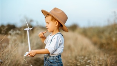 ESG Foto: Kind auf einem Feld mit einem kleinen Windrad in der Hand
