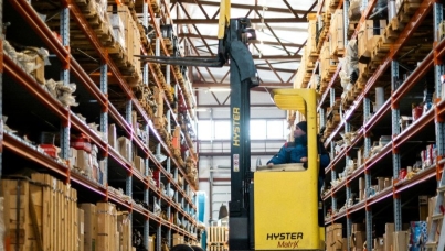 man driving a yello forklift in a warehouse