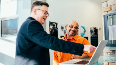 two men in conversation, working together on a laptop