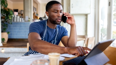 Man wearing apron looking at finances while on the phone