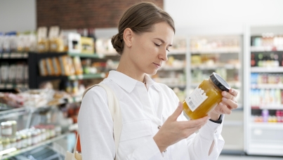 Woman reading ingredients on a bottle in the supermarket