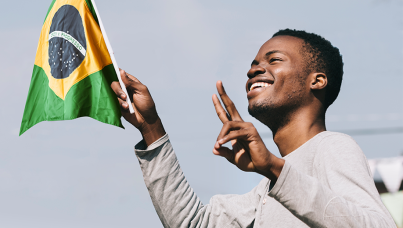 Brasileiro feliz segurando uma bandeirinha do Brasil