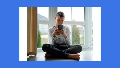 Jovem mexendo no celular sentado no chão de casa