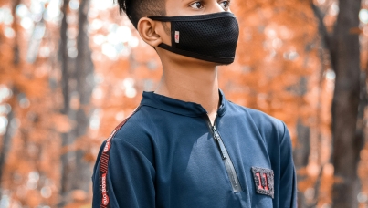 A boy in a forest with a face mask on